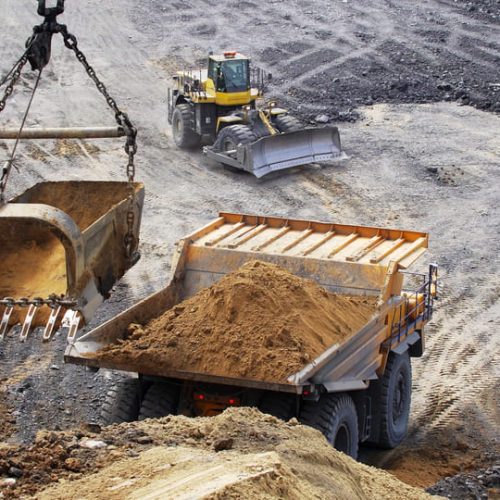 heavy-machinery-is-actively-engaged-in-excavating-soil-on-a-bustling-construction-site-SBI-351114145